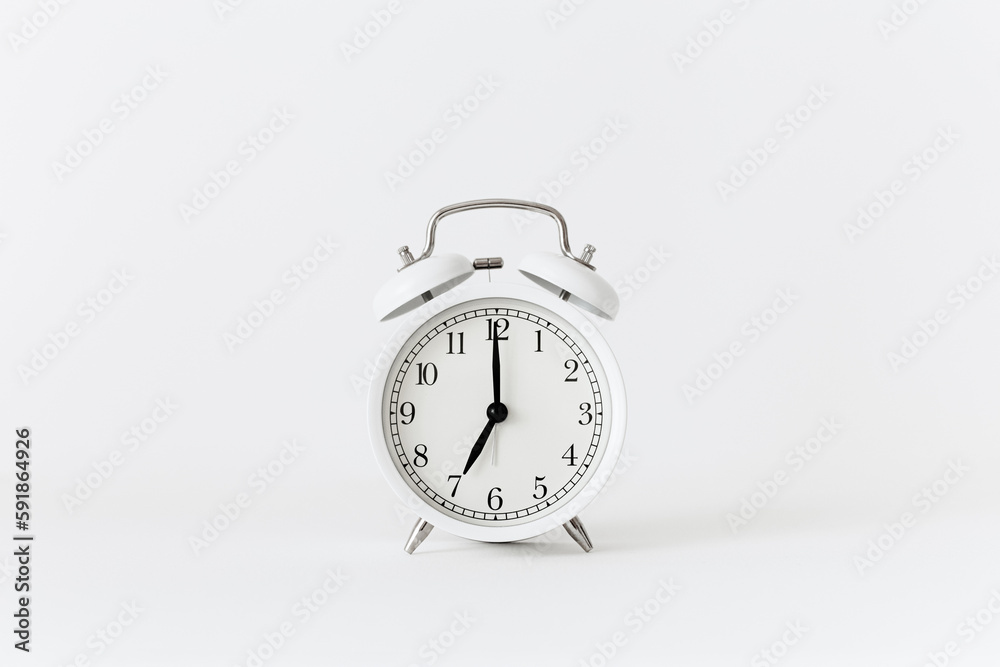 Classic white alarm clock on a white background. Alarm clock show 7 O'Clock with copy space. Classic white alarm clock on a white background. Alarm clock show 7 O'Clock with copy space.