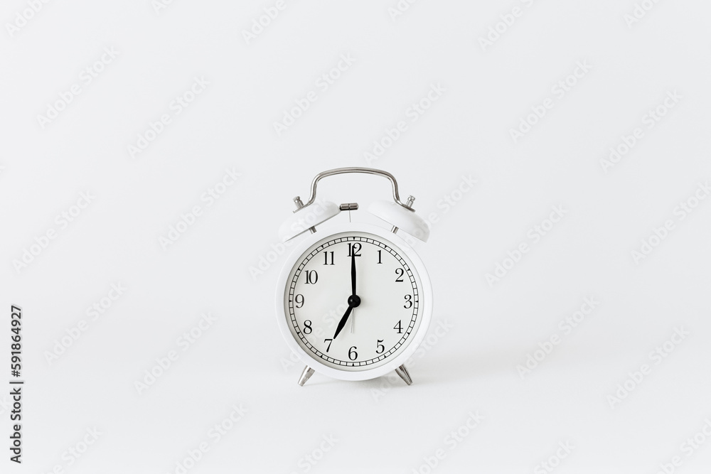 Classic white alarm clock on a white background. Alarm clock show 7 O