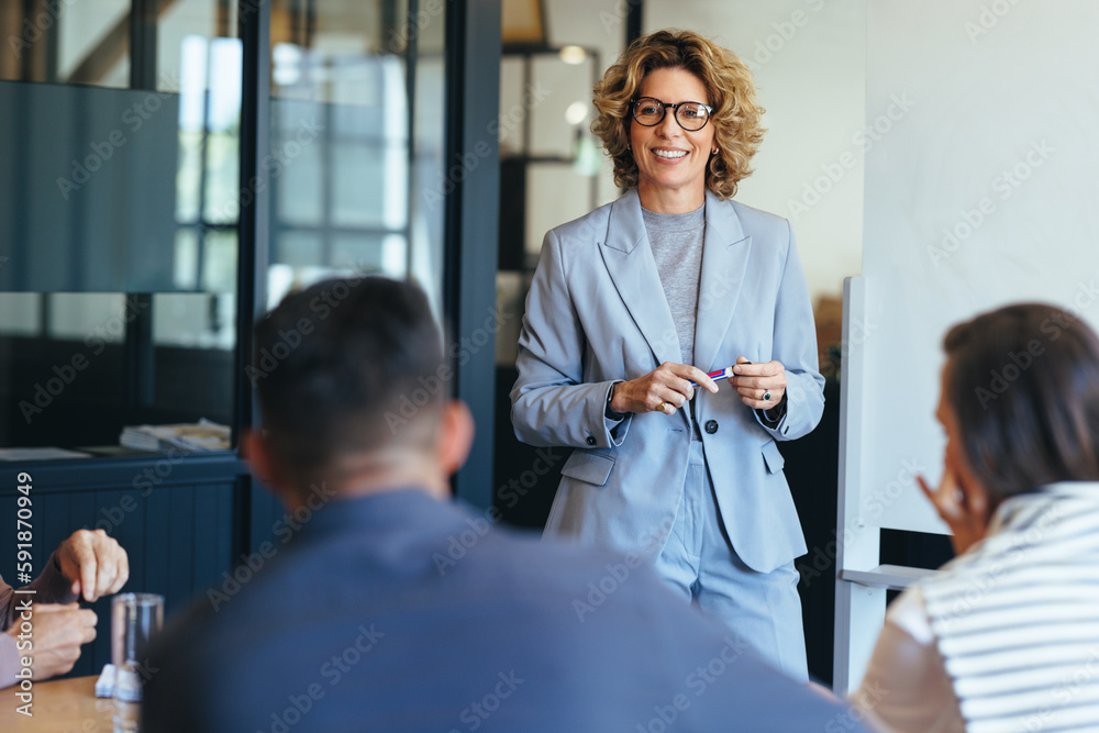 Mature business woman having a discussion with her team. Woman leading a meeting in an office - obrazy, fototapety, plakaty 