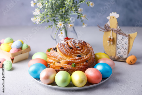 Craffin (Cruffin) with raisins and candied fruits sprinkled with powdered sugar. Traditional Easter Bread Kulich and painted eggs on a gray background. Easter Holiday. Close-up, selective focus. photo