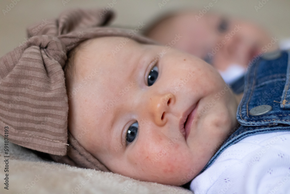 Closeup portrait of a cute Caucasian baby girl with a brown knot turban, lying in bed Closeup portrait of a cute Caucasian baby girl with a brown knot turban, lying in bed