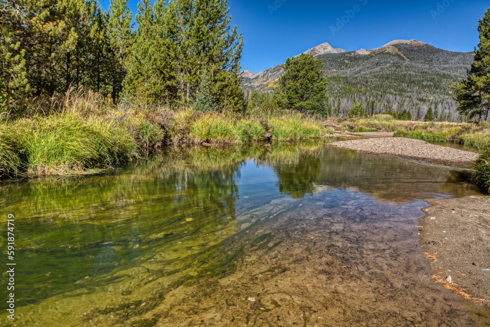 A water stream in the middle of green forest and mountains in Coyote Valley Trail in Colorado A water stream in the middle of green forest and mountains in Coyote Valley Trail in Colorado