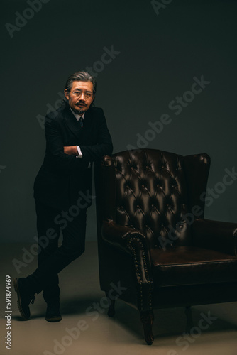 The authoritative old artist stands by the sofa