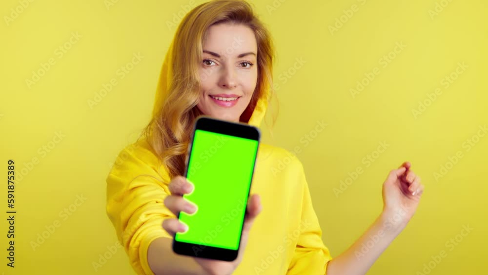 Advertising, green screen, chroma key and woman with phone for product placement, branding and mobile app marketing. Smiling lady female with mobile smartphone, studio isolated on yellow background Advertising, green screen, chroma key and woman with phone for product placement, branding and mobile app marketing. Smiling lady female with mobile smartphone, studio isolated on yellow background