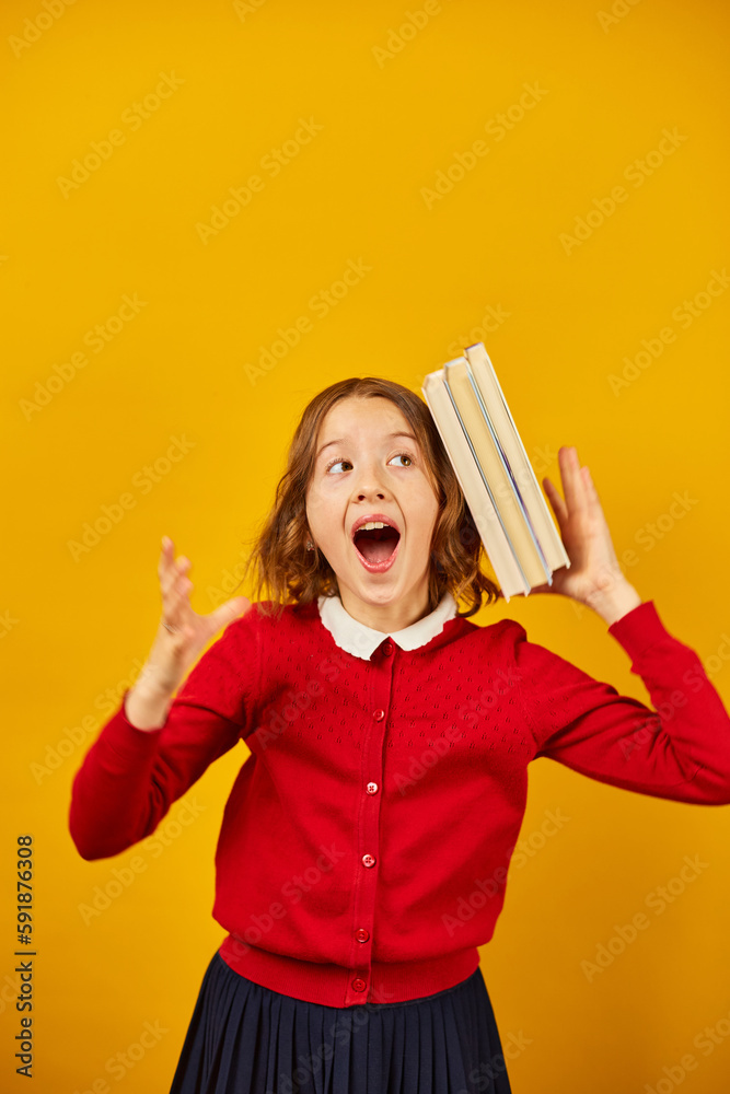 Portrait of happy teenage schoolgirl in uniform holding books on head Portrait of happy teenage schoolgirl in uniform holding books on head