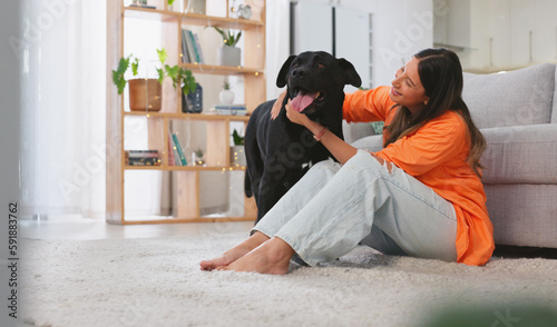 Woman, happiness and dog in a home with pet owner love, support and care feeling relax. Dogs scratch, young female and happy person sitting on a living room floor in a house with a smile and animal © Azeemud-Deen Jacobs/peopleimages.com