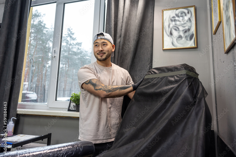 Asian tattoo master preparing couch for tattoo session