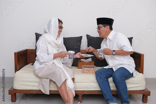 An Indonesian couple is enjoying snack and drink when breaking their fast at home. photo