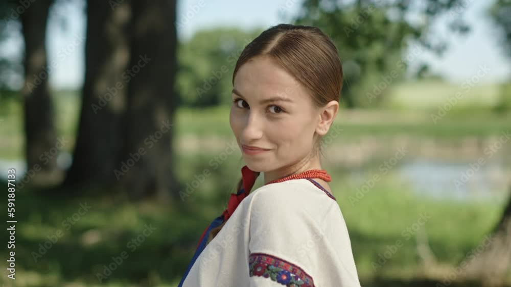 Smiling Ukrainian woman in ethnic costume looking at camera in nature Smiling Ukrainian woman in ethnic costume looking at camera in nature