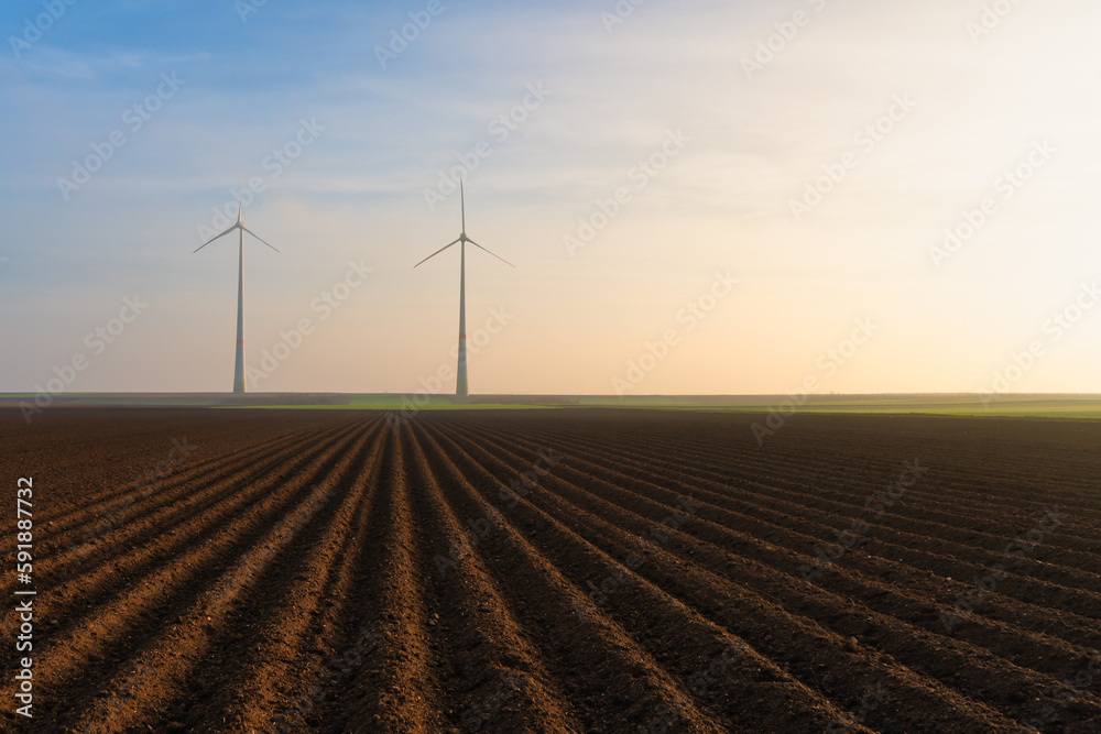 Beautiful shot of windmills in a big farmland under cloudy sky during sunset