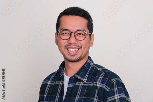 Close up headshot of adult Asian man wearing glasses and smiling friendly © KrishnaTedjo