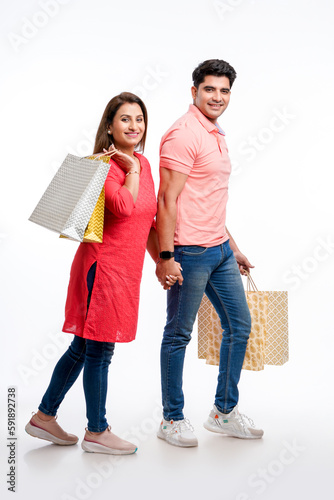 Young indian couple holding shopping bags on white background. © Niks Ads