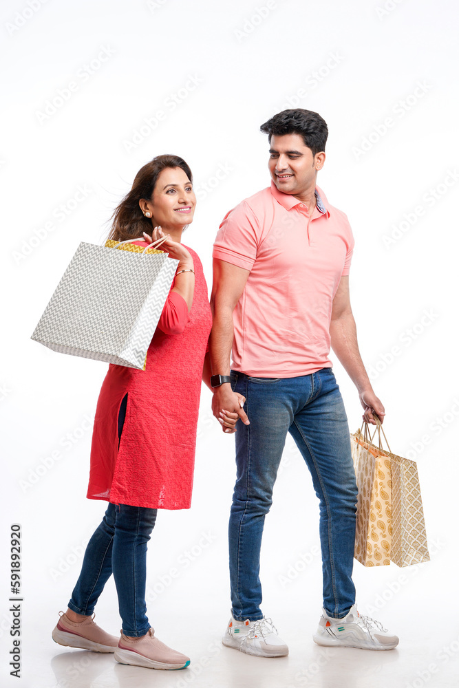 Young indian couple holding shopping bags on white background. Young indian couple holding shopping bags on white background.