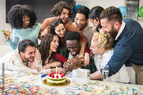 Group of friends hugging the young African American celebrated on his birthday, manifestations of joy friendship and affection of a multiracial group