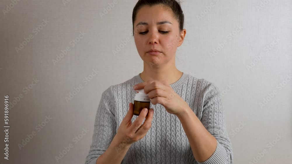 Young woman taking pill, close-up. Woman with bottle of antibiotic Young woman taking pill, close-up. Woman with bottle of antibiotic