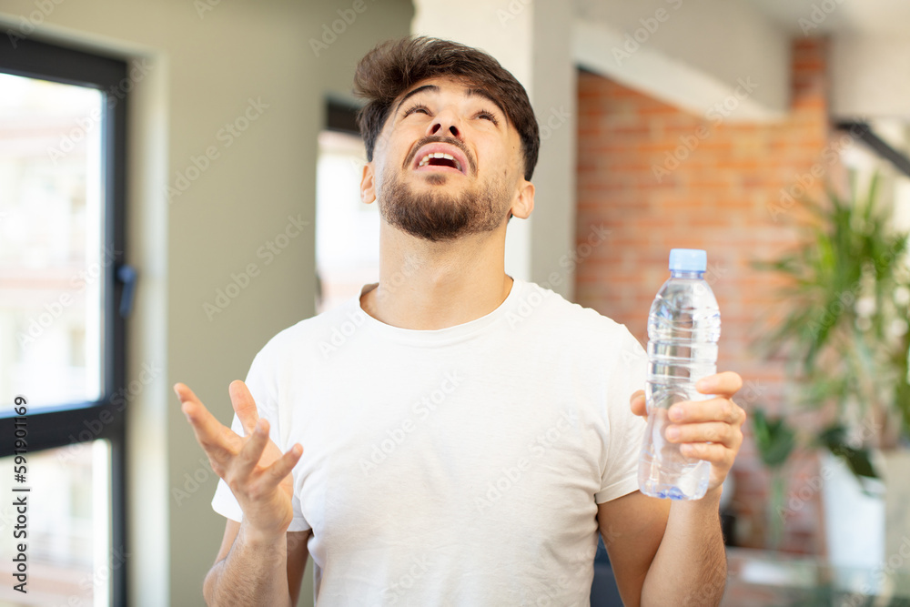 young handsome man screaming with hands up in the air. water bottle concept young handsome man screaming with hands up in the air. water bottle concept
