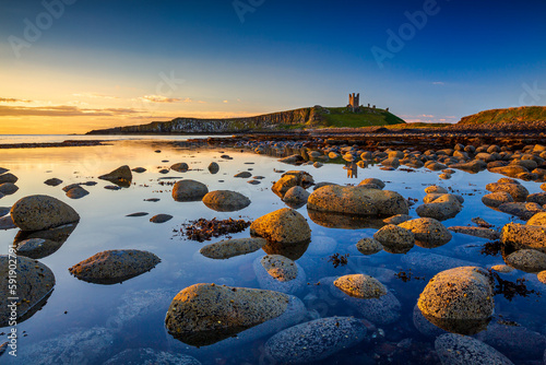 Dunstanburgh Castle at dawn from Embleton Bay, Northumberland, England photo