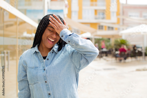 afro pretty black woman laughing and slapping forehead like saying d’oh! I forgot or that was a stupid mistake © kues1