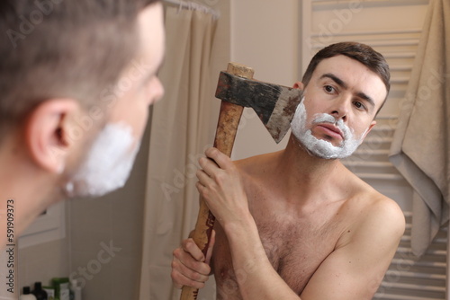 Wild man shaving his beard with an axe