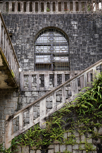 Old ancient stone building with outdoor stairs and ferns grown on