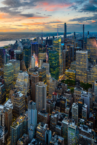 An illuminated midtown of New York City and rainy clouds above in sunset. 