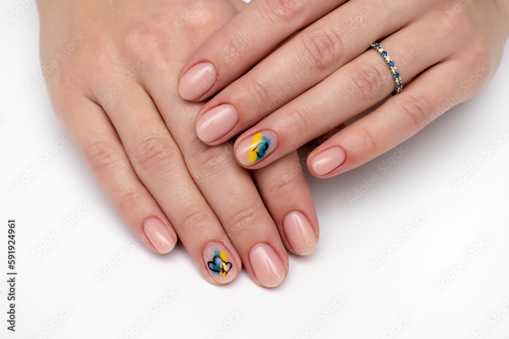 Natural beige manicure on short oval nails. Ukrainian symbols. Yellow blue drawing.