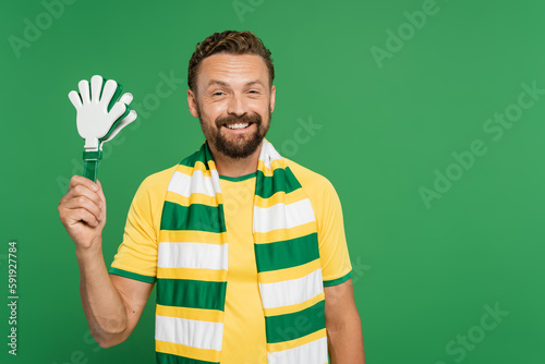Carta da parati cheerful football fan in striped scarf holding plastic hand clapper isolated on green