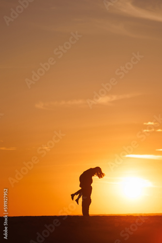 silhouettes of couple at sunset against bright sun sky. man and woman have fun in nature, walking and relaxing, relationships and falling in love. poster postcard romantic meetings against background 
