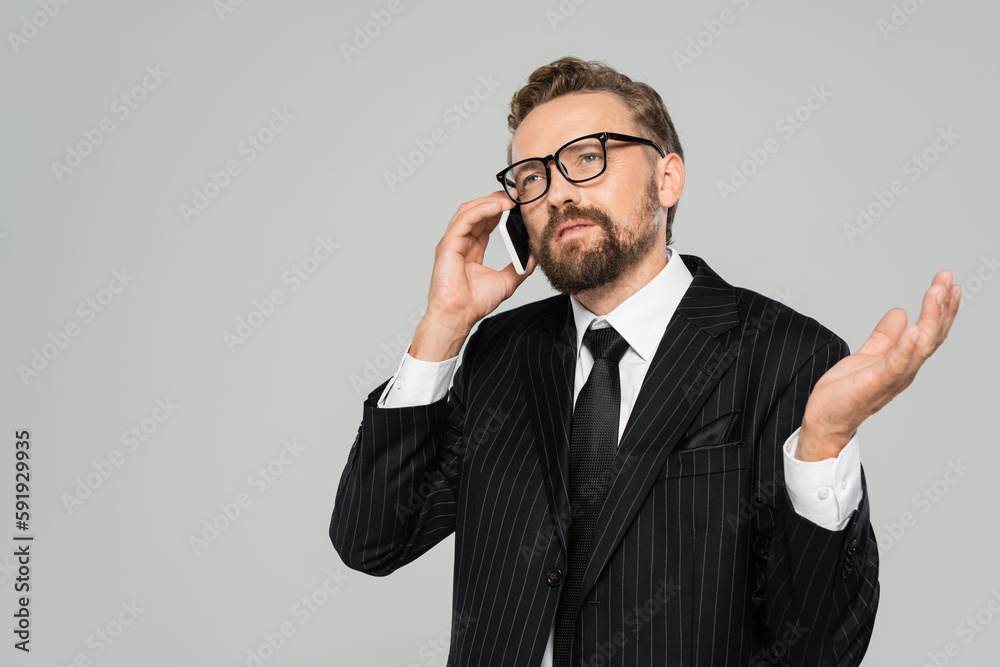 bearded businessman in suit and glasses talking on smartphone isolated on grey. bearded businessman in suit and glasses talking on smartphone isolated on grey.