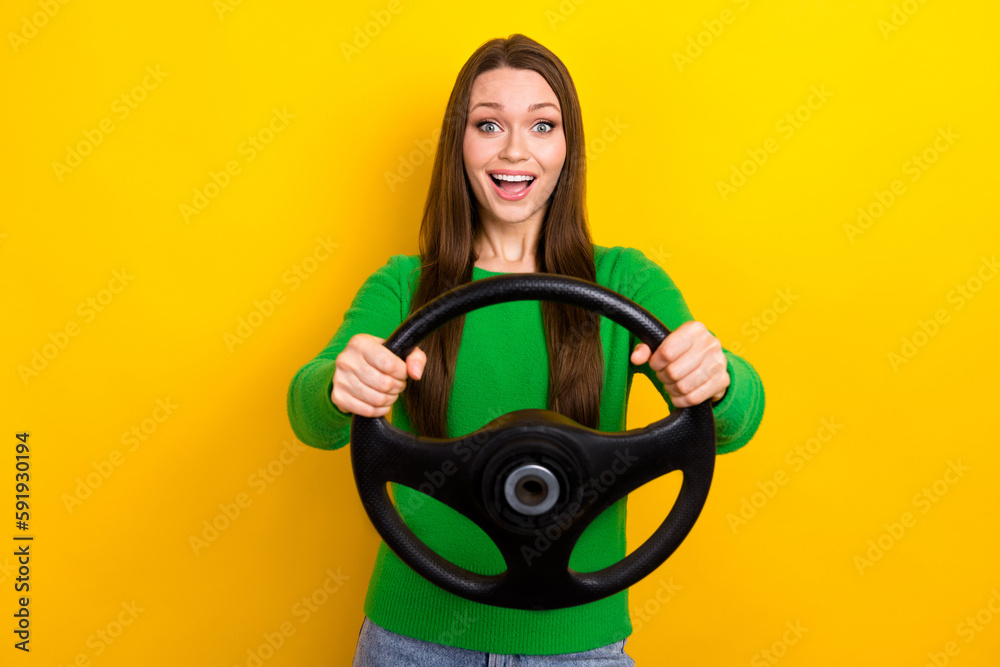 Photo of astonished cheerful girl toothy smile arms hold wheel isolated on yellow color background Photo of astonished cheerful girl toothy smile arms hold wheel isolated on yellow color background