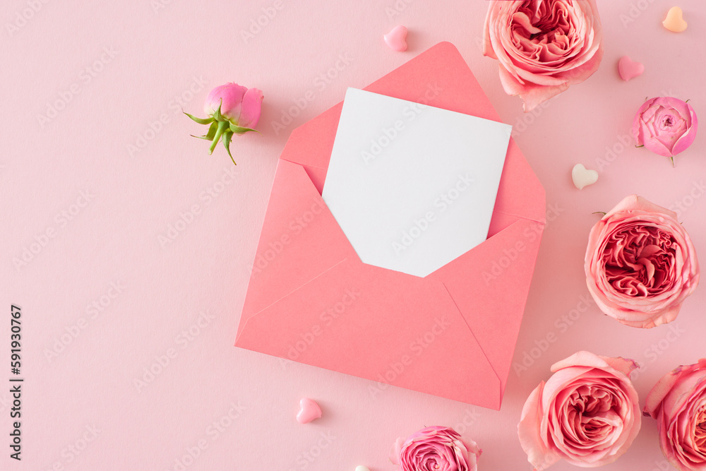 Top view photo of open envelope with white sheet natural flowers pink rose buds and small hearts on isolated light pink background with copy space. Mother's Day celebration idea Top view photo of open envelope with white sheet natural flowers pink rose buds and small hearts on isolated light pink background with copy space. Mother's Day celebration idea