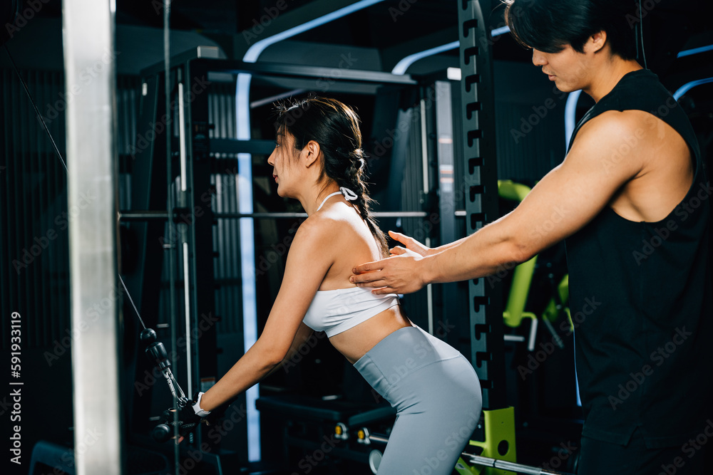 Smiling coach instructing a woman on how to use a pull-down weight machine, focusing on building muscular strength and endurance. GYM healthy lifestyle concept Smiling coach instructing a woman on how to use a pull-down weight machine, focusing on building muscular strength and endurance. GYM healthy lifestyle concept