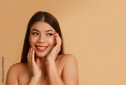 Portrait of beautiful Asian a woman with natural makeup standing over beige background, copy space.