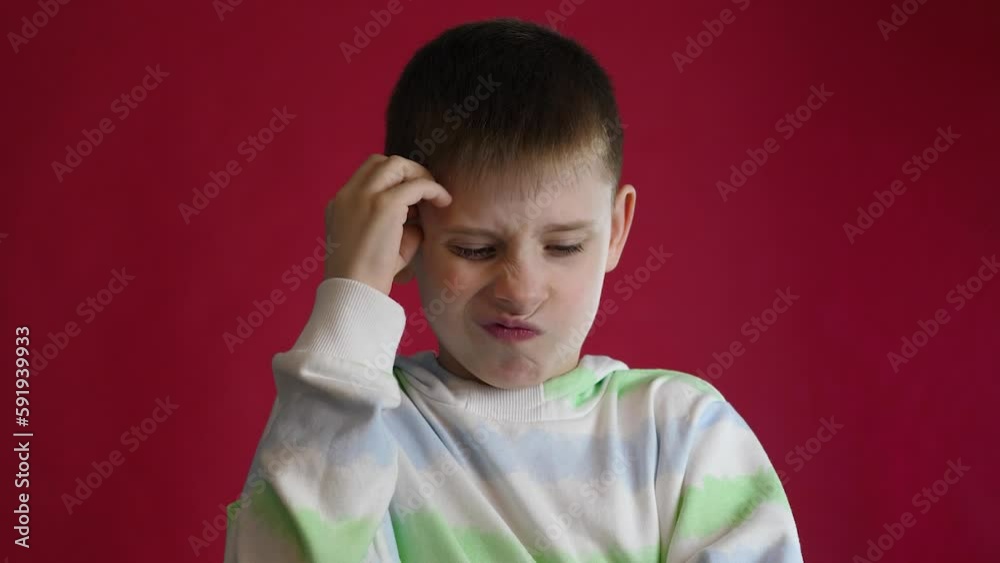 beautiful pensive boy european 9 years old shows a gesture idea looks at the camera .doubtful schoolboy shows a sign found the answer.studio shooting, red background beautiful pensive boy european 9 years old shows a gesture idea looks at the camera .doubtful schoolboy shows a sign found the answer.studio shooting, red background