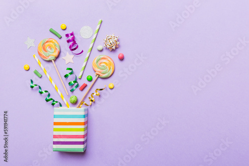 gift box in corner full of assorted traditional candies falling out on colored background with copy space. Happy Holidays sale concept