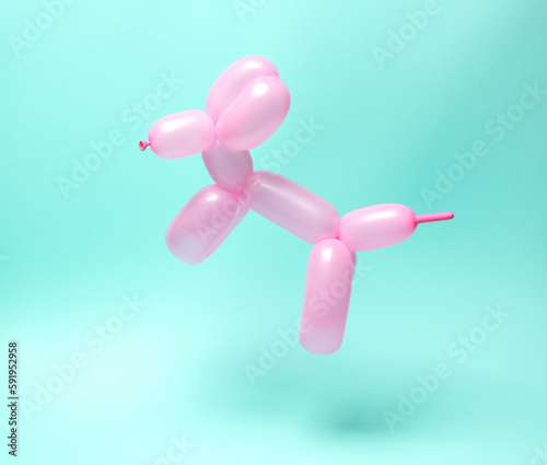 Pink balloon in the shape of dog levitating on blue background.