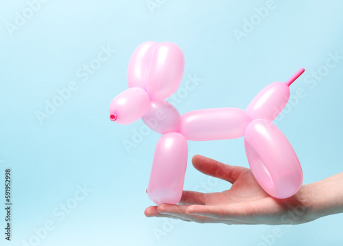 Foto Woman's hand holding balloon dog on blue background