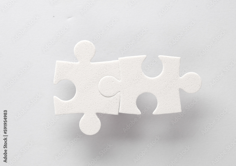 Fototapeta premium White jigsaw puzzle pieces on a gray background.