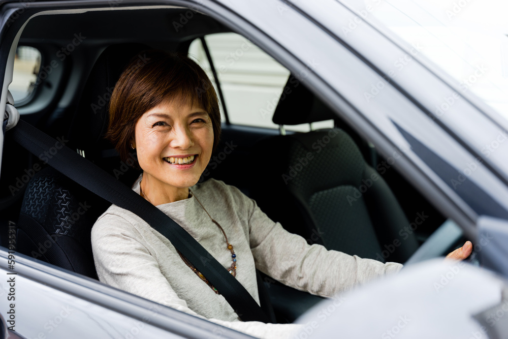 車の運転席に座る50代から60代のカメラ目線の女性