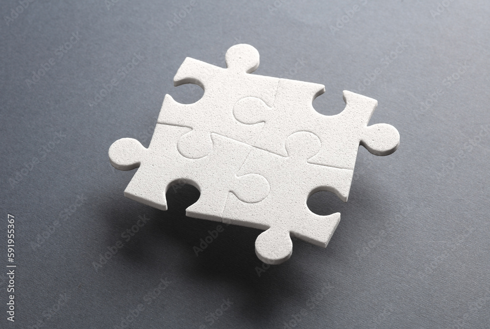 Obraz premium White jigsaw puzzle pieces on dark background.