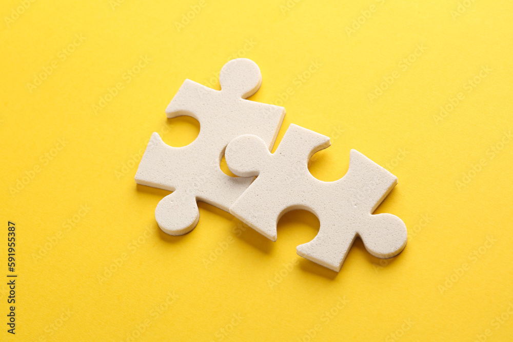 Fototapeta premium White jigsaw puzzle pieces on yellow background.