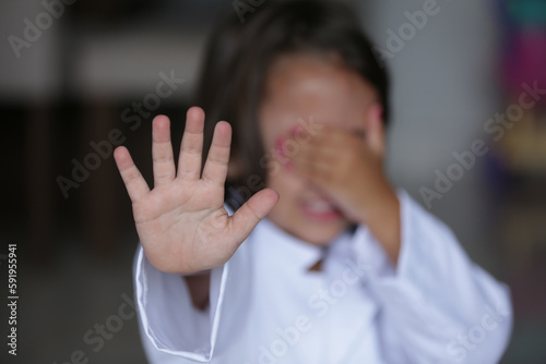 Criança com a mão no rosto sinalizando pare com outramão. photo