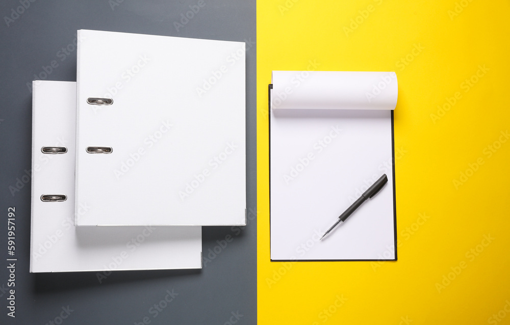 White binder folders and clipboard on a yellow gray background. Business concept. Top view