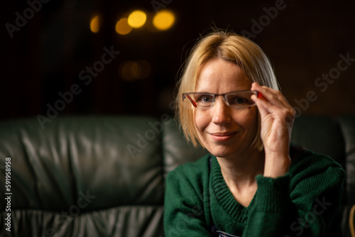 A woman holds glasses in her hands and looks at the camera. Teacher, attention, learning something concept. place for text