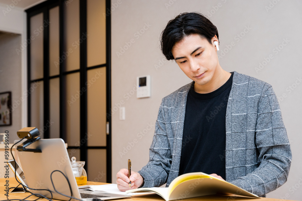 Φωτογραφία 休日に自宅のリビングで資格と語学と英会話の勉強をする30代の社会人の男性