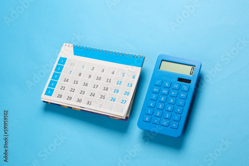 Desk paper calendar organizer with calculator on blue background