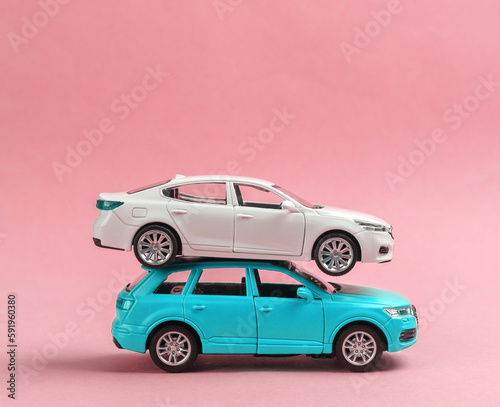 Two toy car models on a pink background