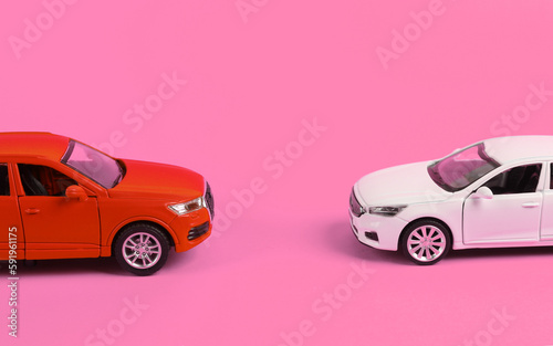 Two toy cars opposite each other on pink background