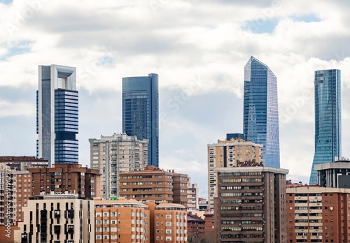 Skyscrapers located in the city of Madrid, Spain, during a cloudy day, rising above the residential buildings. photo