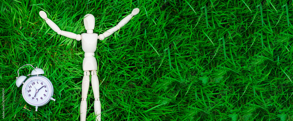 Time for rest, freedom concept. The figure of a man and an alarm clock on the green grass. Banner, place for text. Time for rest, freedom concept. The figure of a man and an alarm clock on the green grass. Banner, place for text.